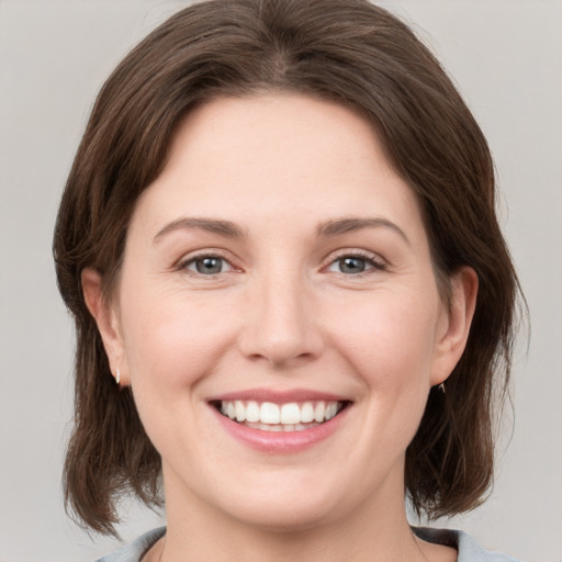 Joyful white young-adult female with medium  brown hair and grey eyes