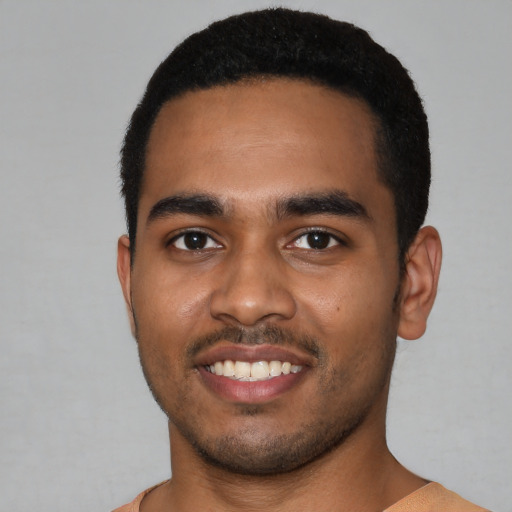 Joyful black young-adult male with short  black hair and brown eyes