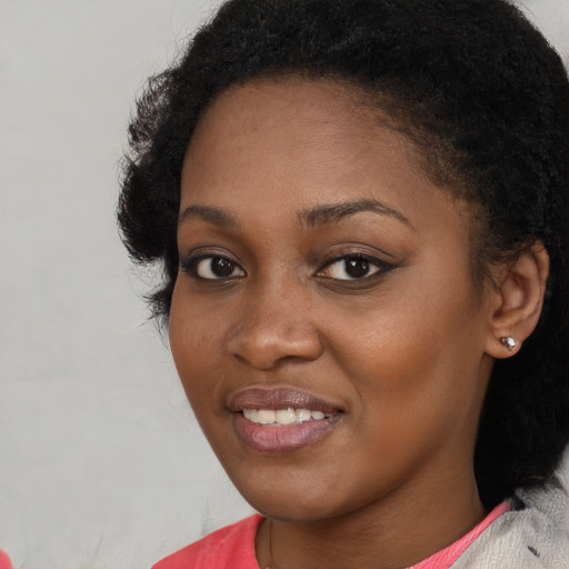 Joyful black young-adult female with short  black hair and brown eyes