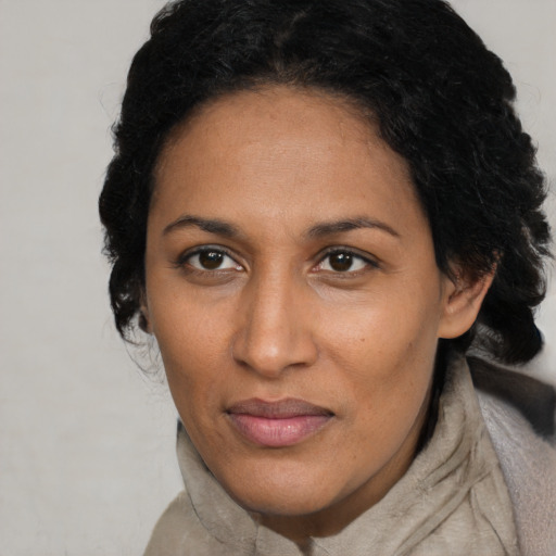 Joyful black adult female with long  brown hair and brown eyes