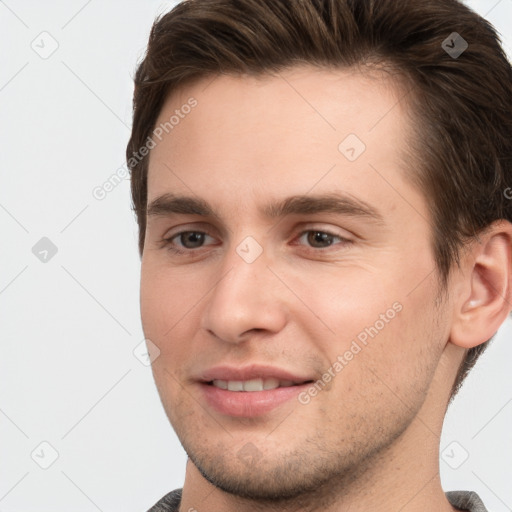 Joyful white young-adult male with short  brown hair and grey eyes