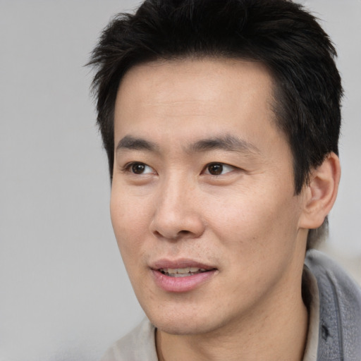 Joyful asian young-adult male with short  brown hair and brown eyes