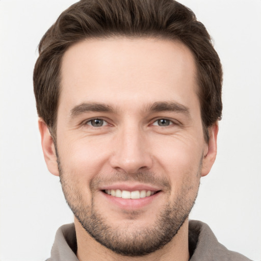 Joyful white young-adult male with short  brown hair and grey eyes