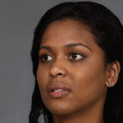 Joyful black young-adult female with long  black hair and brown eyes