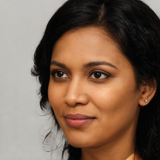 Joyful black young-adult female with long  black hair and brown eyes