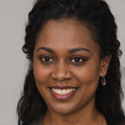 Joyful black young-adult female with long  brown hair and brown eyes