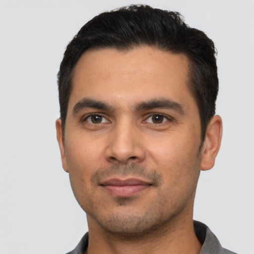 Joyful latino young-adult male with short  black hair and brown eyes