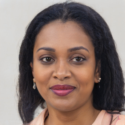 Joyful black young-adult female with long  brown hair and brown eyes