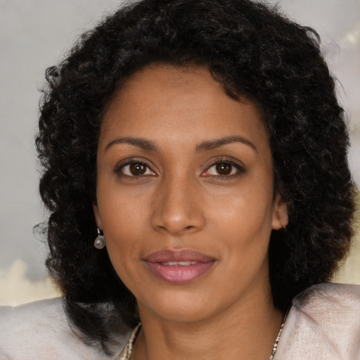 Joyful black young-adult female with long  brown hair and brown eyes