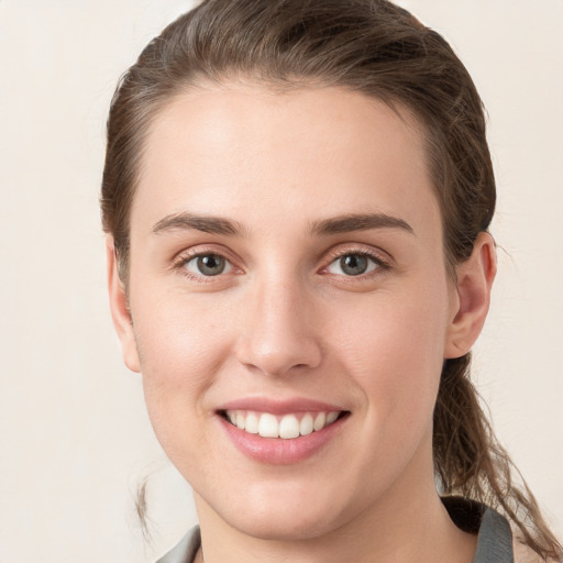 Joyful white young-adult female with medium  brown hair and grey eyes