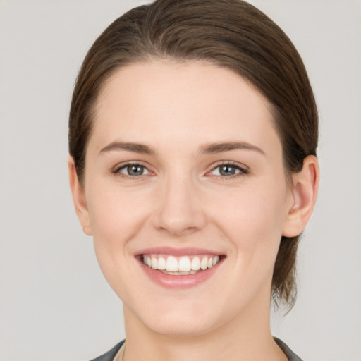 Joyful white young-adult female with medium  brown hair and grey eyes