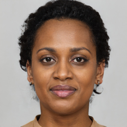 Joyful black young-adult female with short  black hair and brown eyes