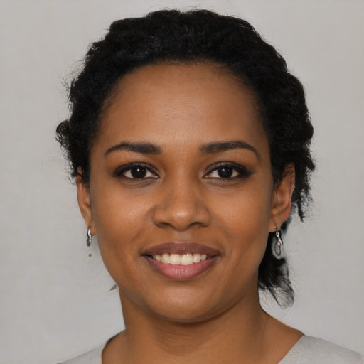 Joyful black young-adult female with short  black hair and brown eyes