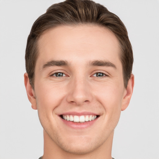 Joyful white young-adult male with short  brown hair and grey eyes