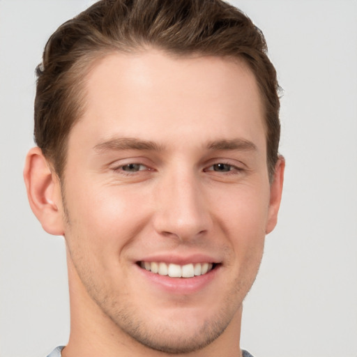 Joyful white young-adult male with short  brown hair and grey eyes