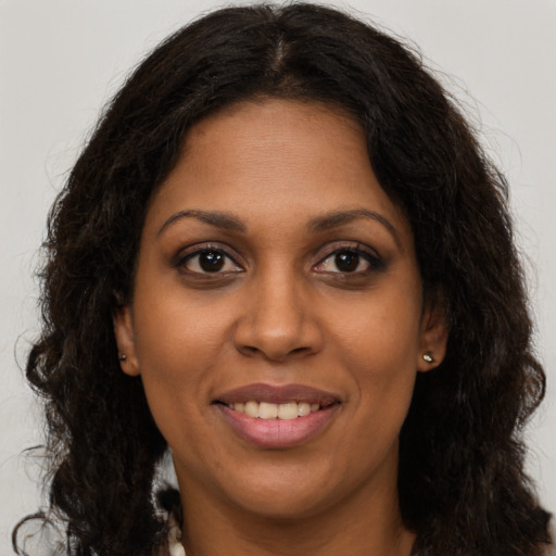 Joyful black young-adult female with long  brown hair and brown eyes