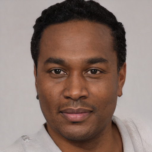 Joyful black young-adult male with short  black hair and brown eyes