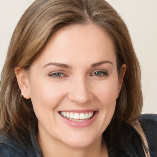 Joyful white young-adult female with medium  brown hair and grey eyes