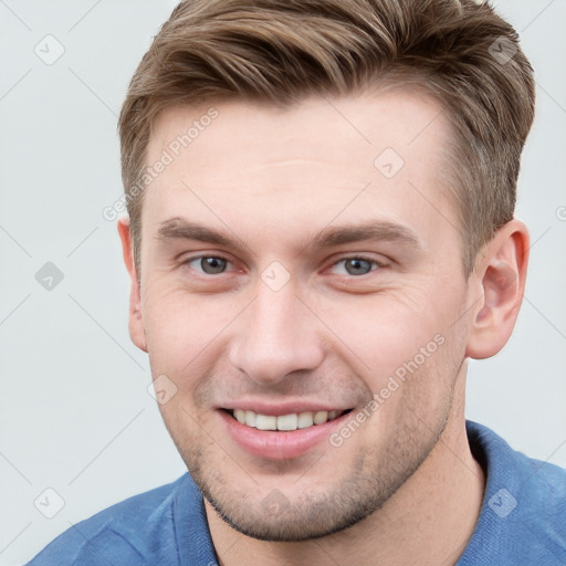 Joyful white young-adult male with short  brown hair and grey eyes