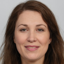 Joyful white adult female with long  brown hair and brown eyes