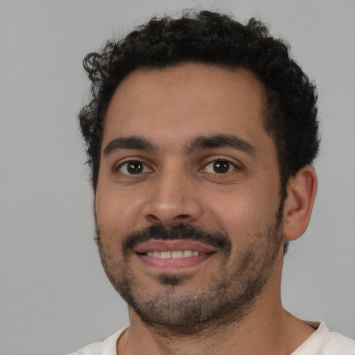 Joyful latino young-adult male with short  black hair and brown eyes