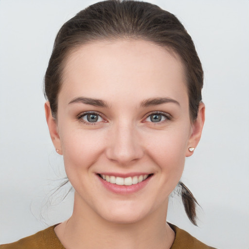 Joyful white young-adult female with medium  brown hair and grey eyes