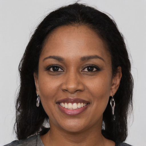 Joyful black young-adult female with long  brown hair and brown eyes