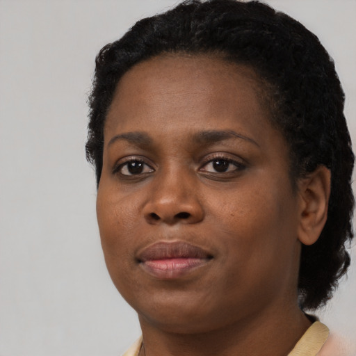 Joyful black young-adult female with short  black hair and brown eyes