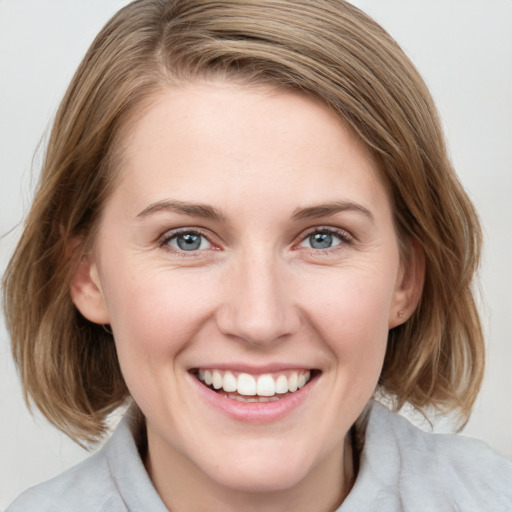 Joyful white young-adult female with medium  brown hair and grey eyes