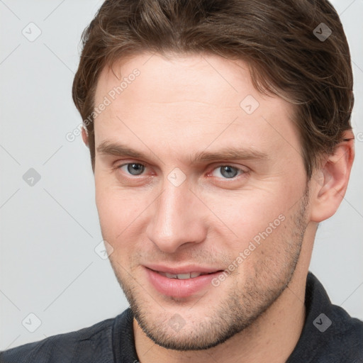 Joyful white young-adult male with short  brown hair and grey eyes