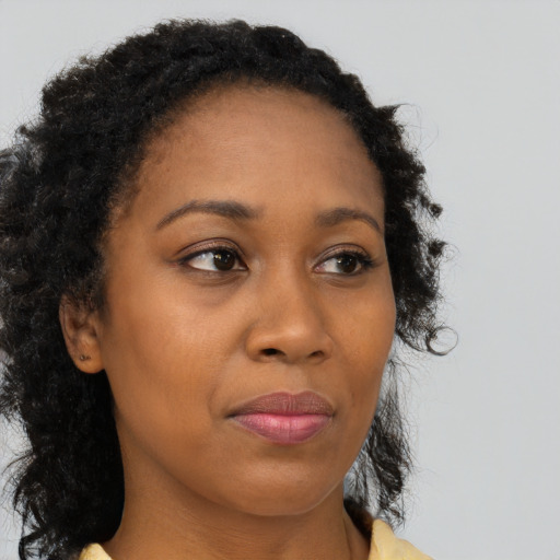 Joyful black young-adult female with long  brown hair and brown eyes
