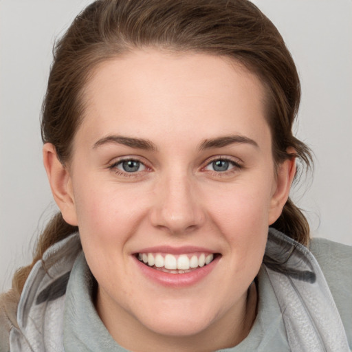 Joyful white young-adult female with medium  brown hair and grey eyes