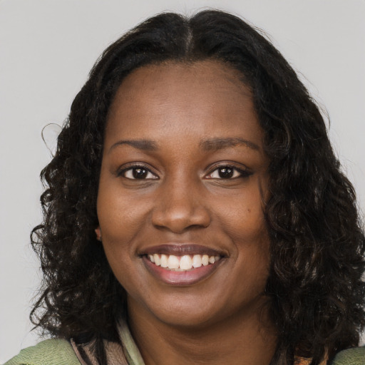 Joyful black young-adult female with long  brown hair and brown eyes