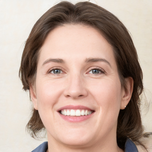 Joyful white young-adult female with medium  brown hair and grey eyes