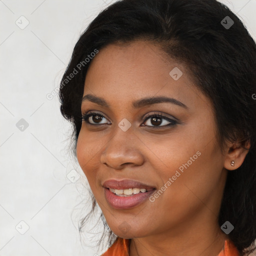 Joyful black young-adult female with long  brown hair and brown eyes