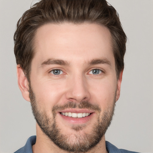 Joyful white young-adult male with short  brown hair and grey eyes