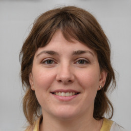 Joyful white young-adult female with medium  brown hair and grey eyes