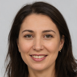 Joyful white adult female with long  brown hair and brown eyes