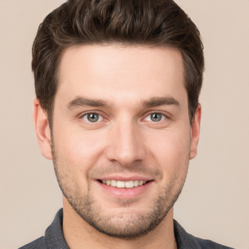 Joyful white young-adult male with short  brown hair and grey eyes