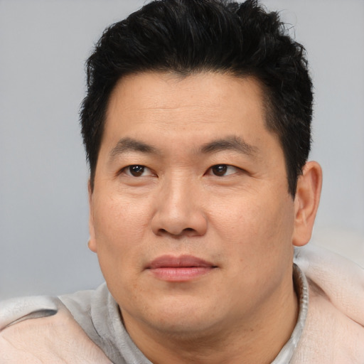 Joyful asian adult male with short  brown hair and brown eyes