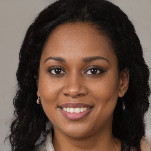 Joyful black young-adult female with long  brown hair and brown eyes