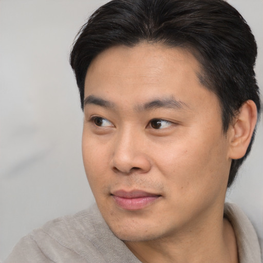 Joyful asian young-adult male with short  brown hair and brown eyes
