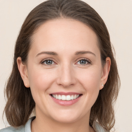 Joyful white young-adult female with medium  brown hair and grey eyes