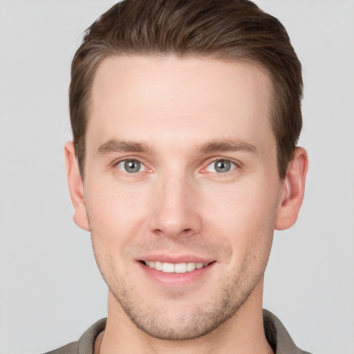 Joyful white young-adult male with short  brown hair and grey eyes