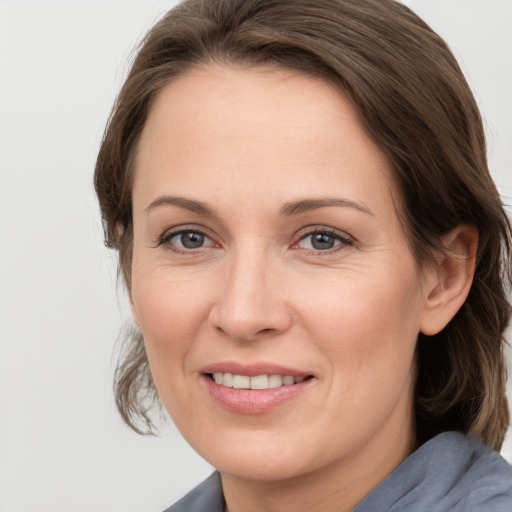 Joyful white adult female with medium  brown hair and grey eyes