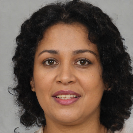 Joyful latino adult female with medium  brown hair and brown eyes
