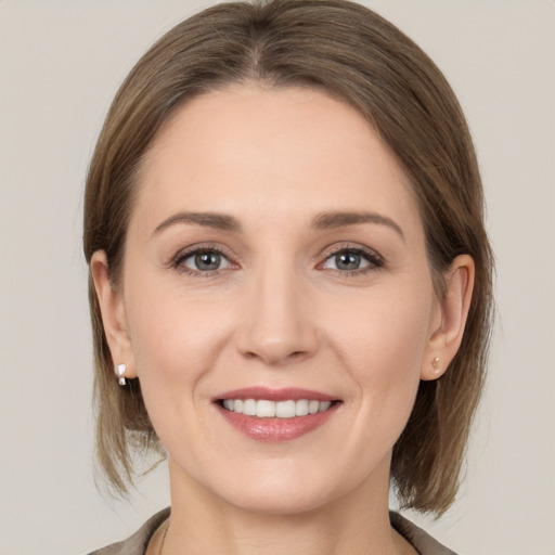 Joyful white young-adult female with medium  brown hair and grey eyes