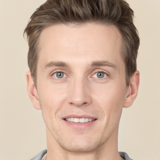 Joyful white young-adult male with short  brown hair and grey eyes