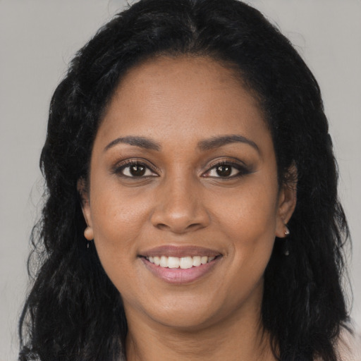 Joyful black young-adult female with long  black hair and brown eyes