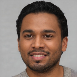 Joyful latino young-adult male with short  black hair and brown eyes